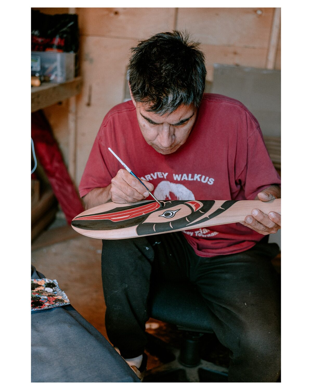 Ross Henderson painting a carved paddle in his workshop